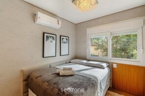 A bedroom with a bed, air conditioning unit, framed pictures, and a window with a view. - Beautiful 2 Bedroom Apartment in Canela Dal207 (Canela)