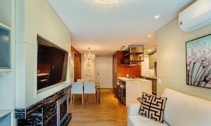A modern living room with a fireplace, a dining area, and a kitchen.