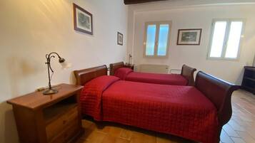 Un dormitorio con dos camas, una mesita de noche de madera, un escritorio y un radiador.