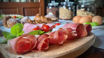 Ein Holzschneidebrett mit geschnittenem Rohbau, Tomaten und Basilikumblättern.