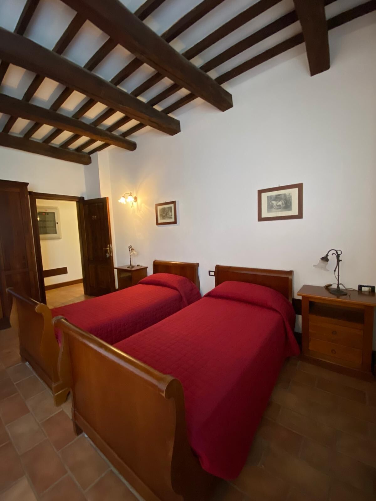 Une chambre à coucher avec deux lits en bois, une table de chevet en bois, une lampe fixée au mur et un tableau encadré accroché au mur.