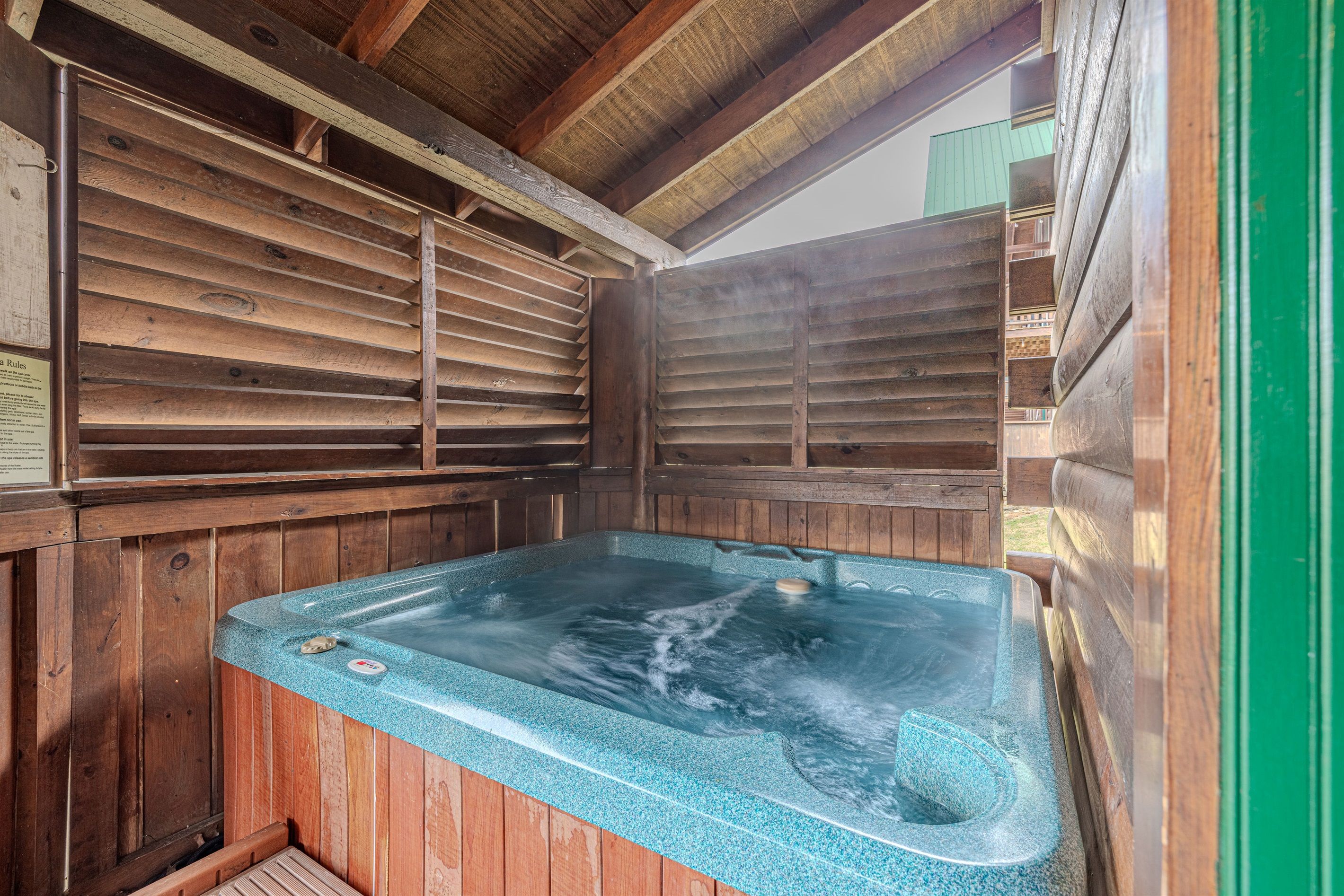A wooden spa with a hot tub, wooden walls, and a sloped ceiling.