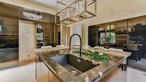 Een moderne keuken met een centraal eiland, roestvrijstalen apparatuur en een decoratieve plantenopstelling.