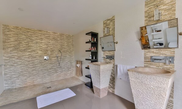 A modern bathroom with a stone wall, a freestanding bathtub, a large sink, and a mirror with a wooden frame. - Chateau Pernelle - Seven Bedroom Villa, Sleeps 14 (Val d’Oise)