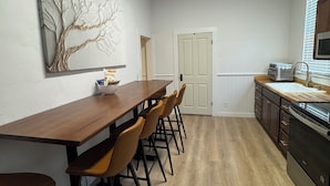 Una cocina moderna con una mesa de comedor de madera, sillas y un microondas.