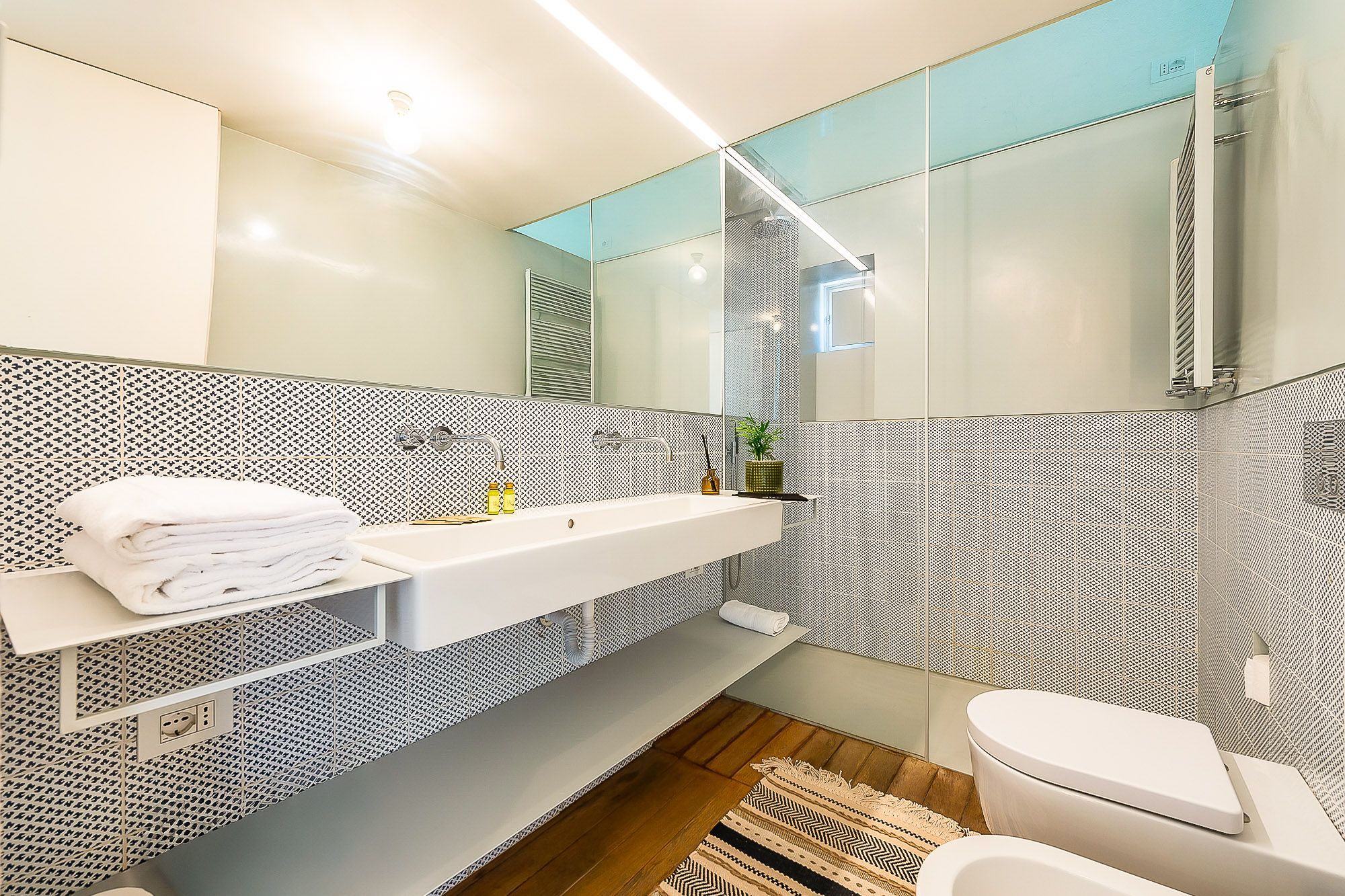 A modern bathroom with a white sink, a toilet, and a shower area.