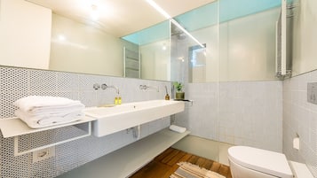 A modern bathroom with a white sink, a toilet, and a shower area.