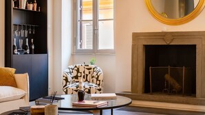 A living room with a fireplace, a sofa, a coffee table with books and a vase, and a bookshelf with decorative items. - Skylife Cimarra - Three Bedroom Villa, Sleeps 6 (Rome)