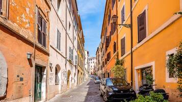 A narrow cobblestone street flanked by buildings with arched doorways and shutters.