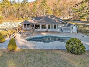 A house with a covered deck, a swimming pool, and a small shed.