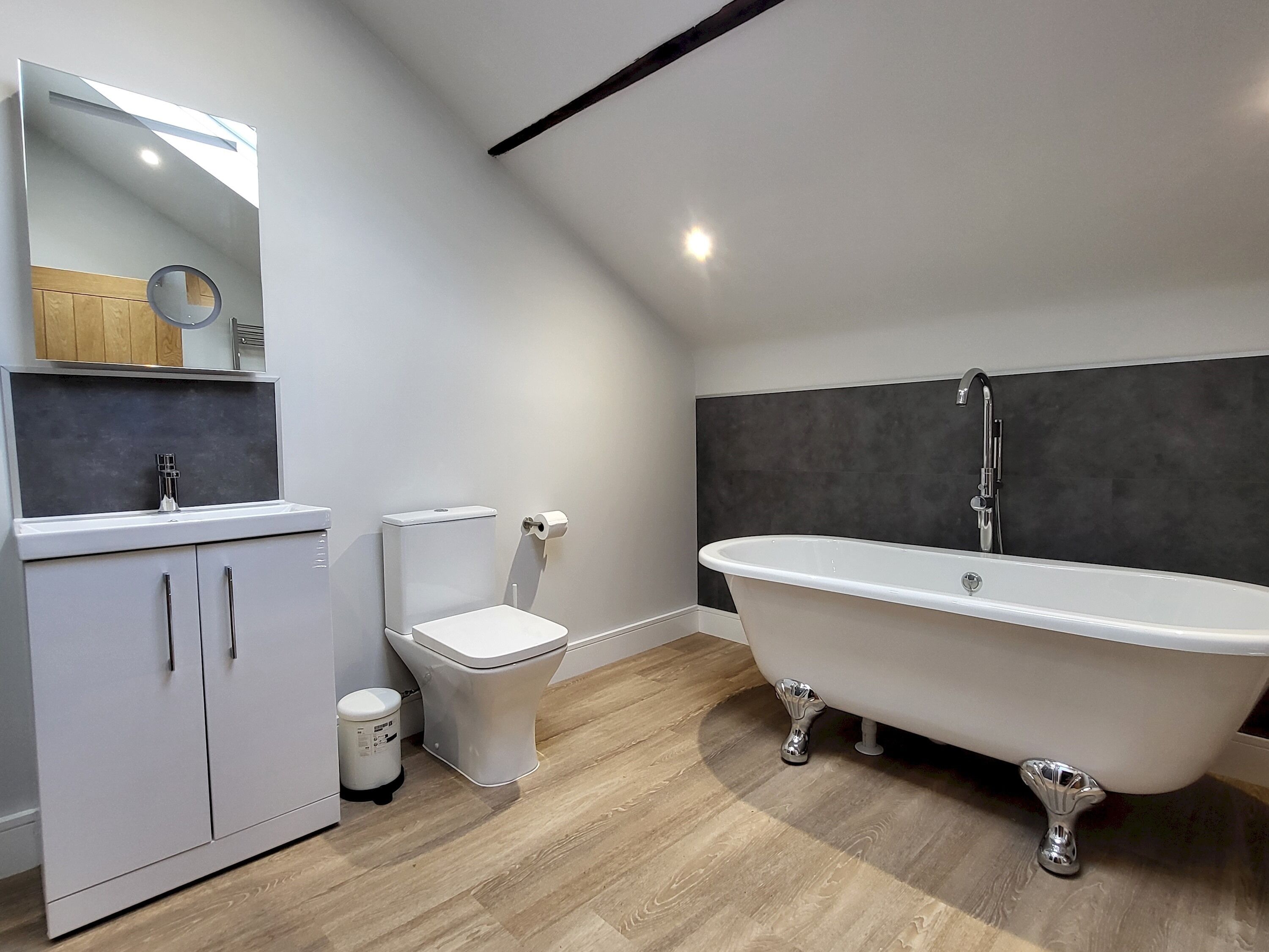 Ein modernes Badezimmer mit freistehender Badewanne, Toilette und einem Waschtisch mit Schränken.