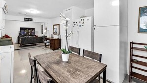 Een moderne keuken met witte apparaten, een eettafel met stoelen, een potplant en een bankje.
