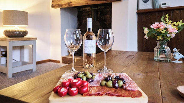 Une table en bois, une planche de charcuterie, une bouteille de vin Pinot Grigio et deux verres.