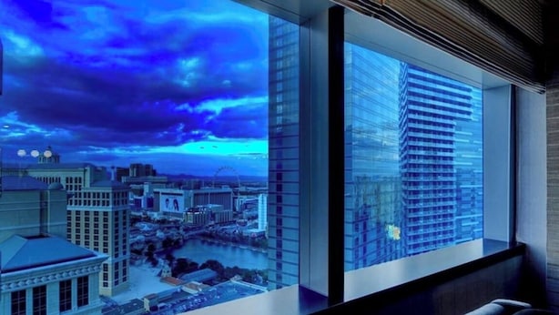 Un intérieur moderne avec de grandes fenêtres donnant sur un paysage urbain et une rivière.