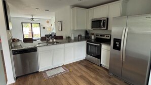 A modern kitchen with white cabinets, stainless steel appliances, and a wooden floor. - Pet-Friendly 3BR w/ Garage & Fenced Yard-Near Beaches (North Port)