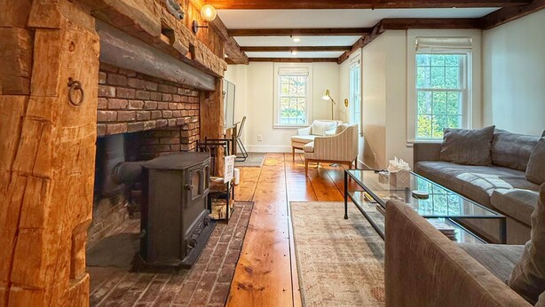 A cozy living room with a fireplace, wooden beams, and a sofa. - Family Fun in Yarmouth Port (Yarmouth)