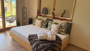 A bedroom with a wooden bed, a view of the outdoors through a sliding door, and a small potted plant on the nightstand. - Vacation home in a secluded location for relaxing and active vacations (Patersdorf)