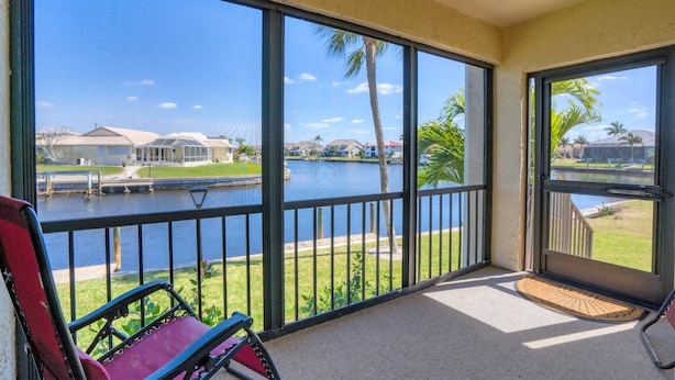 A balcony with a view of a lake, a chair, and a door leading to another room.