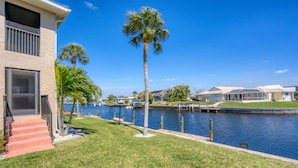 A waterfront property with a grassy lawn, palm trees, and a marina.