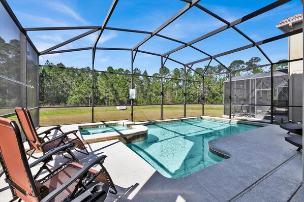An outdoor swimming pool with a covered area, surrounded by chairs and a view of a forested area. - BPD2920 Summary:<br>Para (Kissimmee)