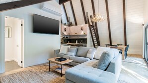 Un salon moderne avec un canapé gris, un téléviseur à écran plat et une table basse en bois.
