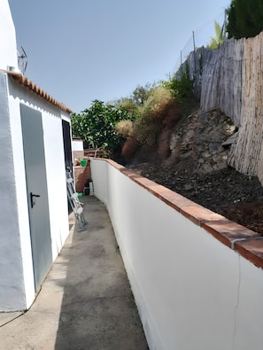 Un couloir étroit avec un mur blanc, une porte et une petite marche menant à un espace abrité.