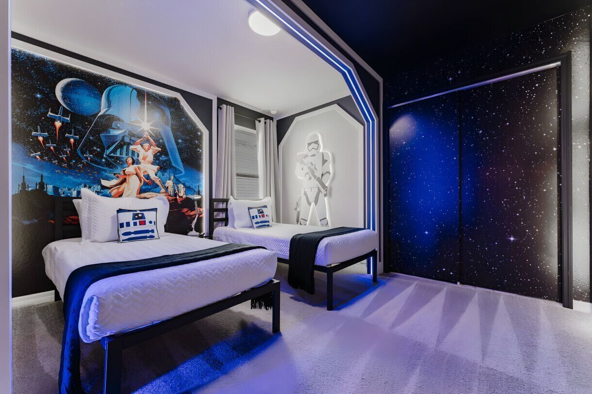 Ein Schlafzimmer mit zwei Betten, einer Wandmalerei zum Thema Star Wars und einer Sternenhimmel-Wand.