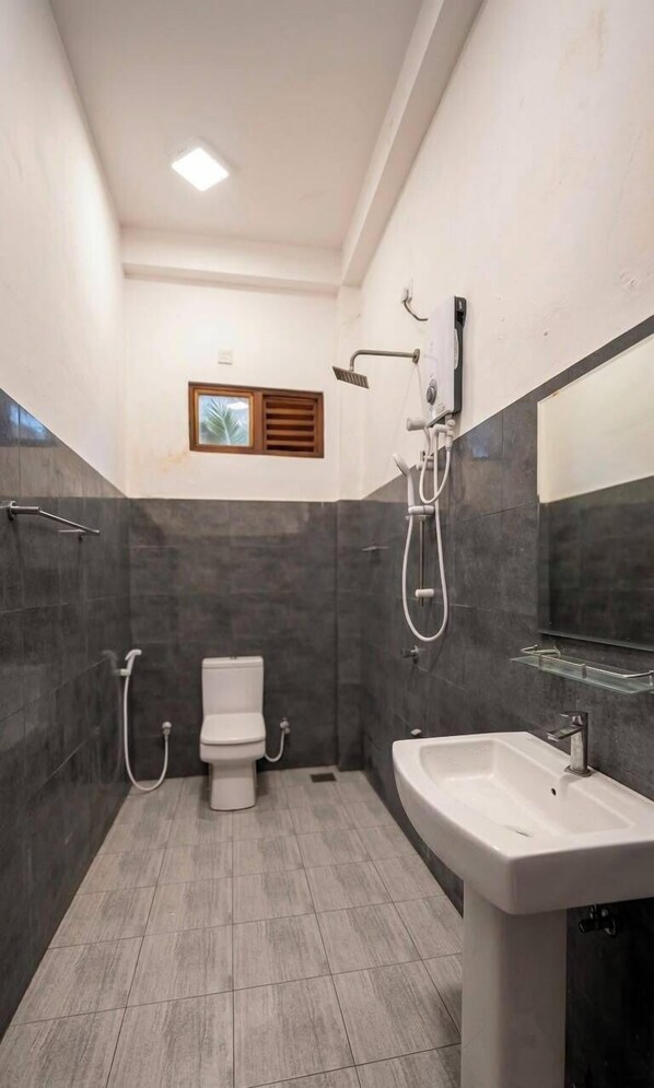 Een badkamer met toilet, douche en wastafel.