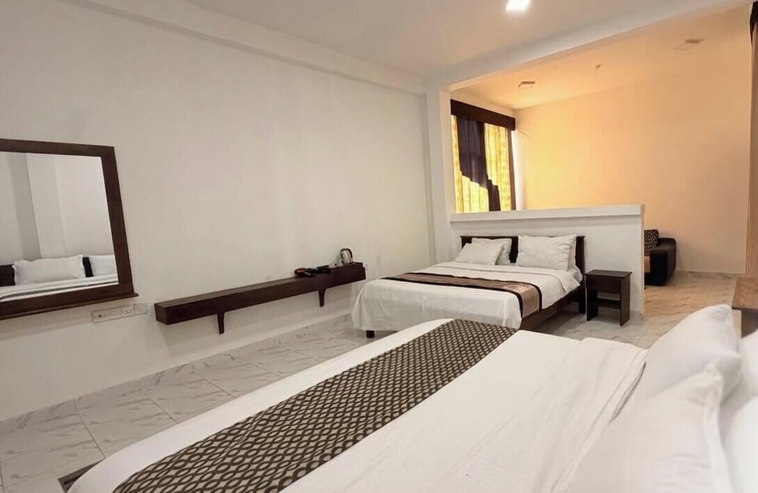 Habitación de hotel con una cama grande, una mesita de noche, un espejo y una ventana con cortinas.