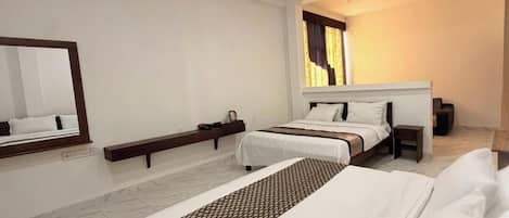 Habitación de hotel con una cama grande, una mesita de noche, un espejo y una ventana con cortinas.
