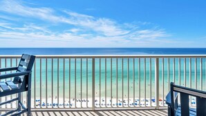 A balcony with a view of a beach and ocean.