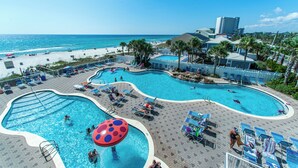 A resort with multiple swimming pools, beach access, and palm trees.