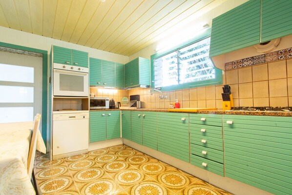 A kitchen with teal cabinets, a microwave, a stove, and patterned floor tiles. - Mediterranean heaven with sea views (Alella)