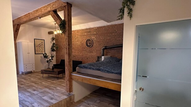 A room with a bed, a wooden bench, a clock, and a door. - ‼️WOW chic Loftwohnung‼️Wifi, minibar (Erfurt)