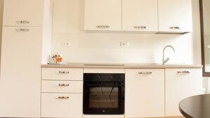 Een moderne keuken met witte kasten, een zwarte oven en een roestvrijstalen spoelbak.