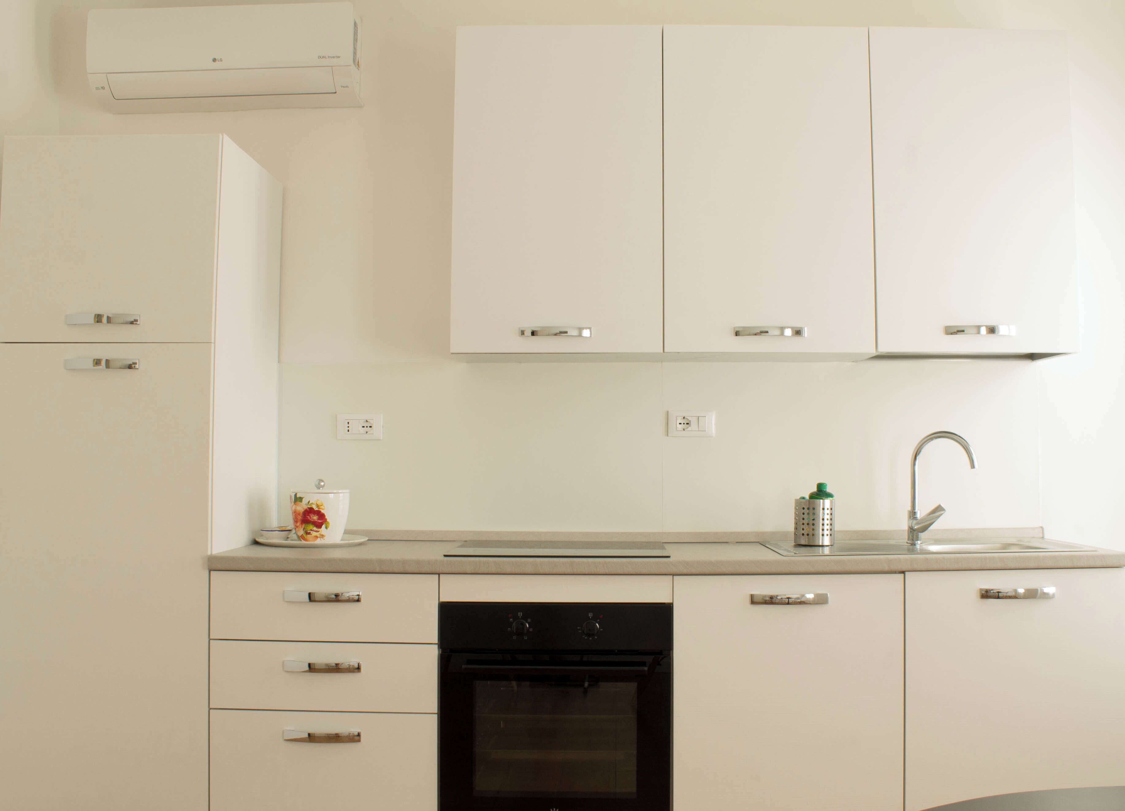 A modern kitchen with white cabinets, a black dishwasher, a stainless steel sink, and a small decorative item on the counter.