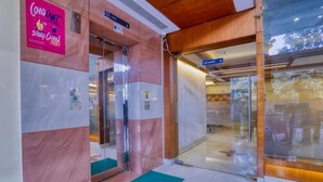 A hotel entrance with a lift, a restaurant sign, and a COVID-19 safety sign. - Hotel Amrit Residency (Indore)