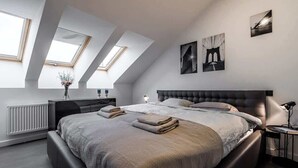 A modern bedroom with a large bed, skylights, and artwork on the walls. - Domillion cozy 3bdr apt in oldtown P364b (Vilnius)