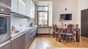 Una cocina moderna con horno integrado, un ventanal grande y un comedor con sillas de madera y una mesa.