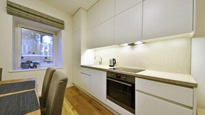 A modern kitchen with white cabinetry, a built-in oven, and a window with a view of the outside.
