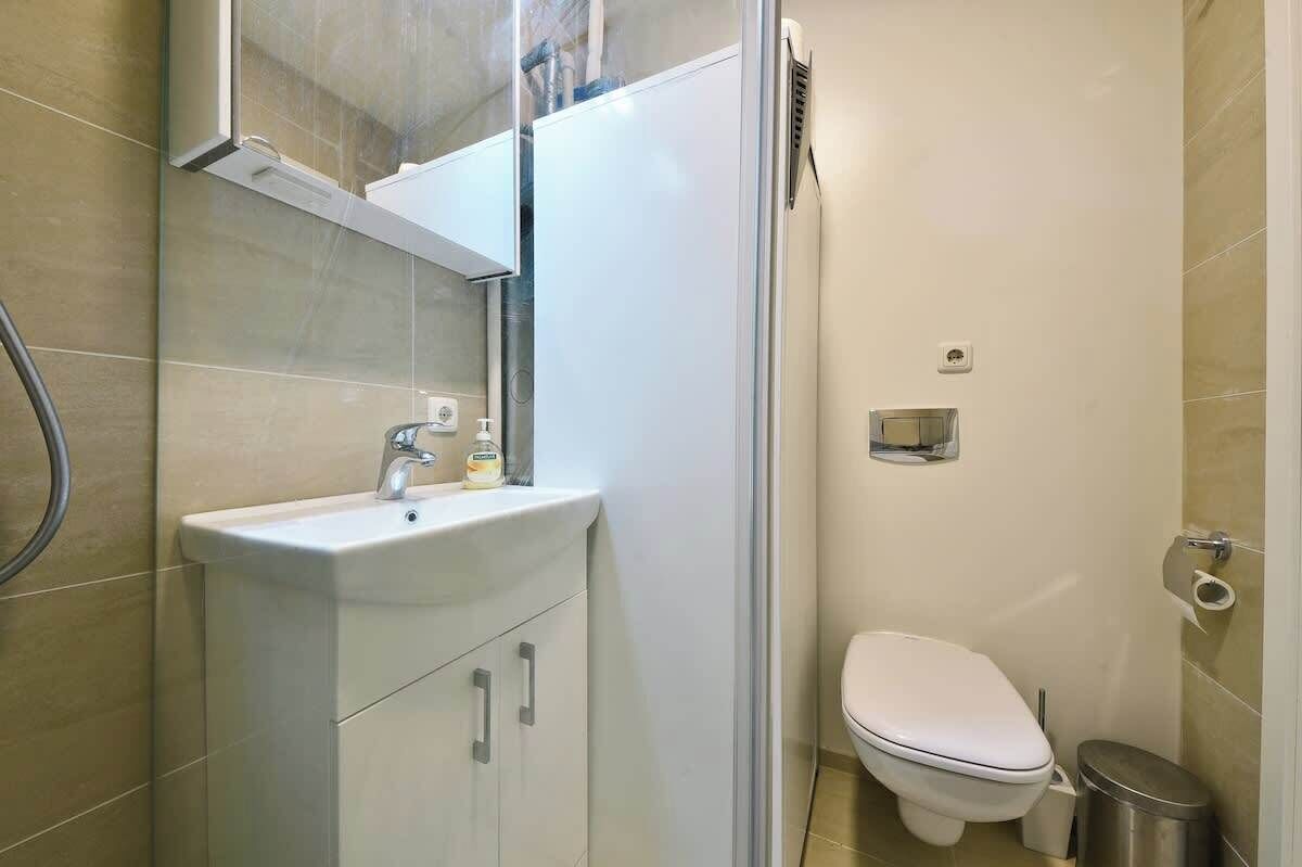 A compact bathroom with a white sink, mirror, and toilet.