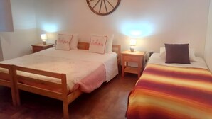 A bedroom with two beds, a wooden headboard, bedside tables with lamps, and a wall-mounted decorative wheel. - Room 'Palmeira' with Shared Pool, Wi-Fi and Air Conditioning (Mina de São Domingos)