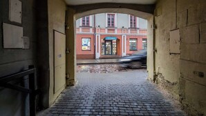 An arched passageway leading to a building with a 'Droges' sign, cobblestone floor, and a brick wall. - Domillion 1bdr unique and warm Old Town apt Tr41 (Vilnius)