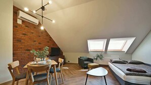 A loft-style room with a dining area, a sofa, and a bed.