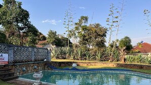 A swimming pool with a stone wall and a signboard.