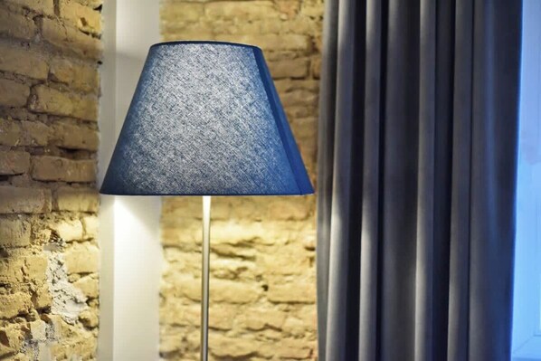 A floor lamp with a textured blue shade against a brick wall and a window with curtains. - Domillion 2bdr President Palace free parking L417 (Vilnius)