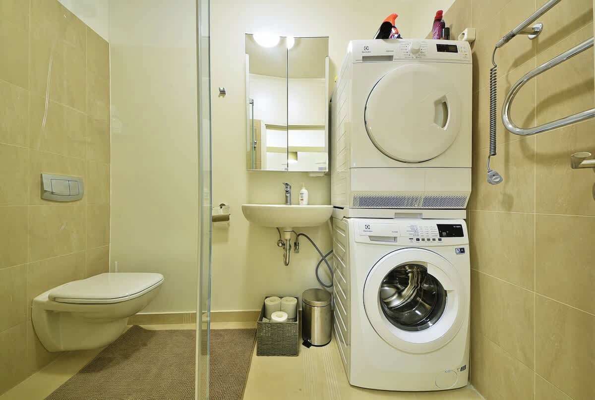 A compact bathroom with a toilet, sink, and stacked washer and dryer.