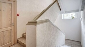 A staircase with a wooden door and a small window with a plant. - Zemaitijos Versatile 12ppl Triplex (Vilnius)