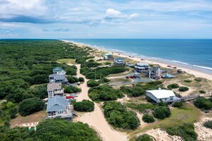 A coastal property with multiple houses, a beach, and a pier.