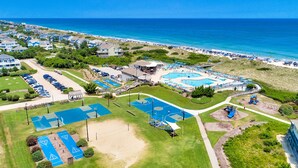 Vista aérea de un resort con varias piscinas, una playa y un estacionamiento.